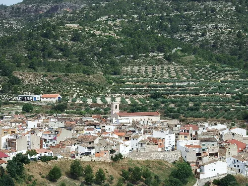 Blick auf eine Stadt mit weißen Häusern und terrassierten Feldern an den Hügeln.