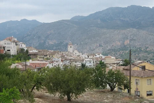 View of a town with houses, church, and mountains in the background.