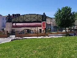 Sebastián Martos sports pavilion in Huelma, Jaén, with green areas and trees.