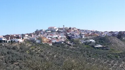 Panoramablick auf ein Hügeldorf mit weißen Häusern und ländlichen Wegen.