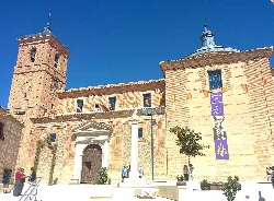 Fassade der Kirche San Pedro und San Pablo in Polán mit Turm und blauem Himmel.