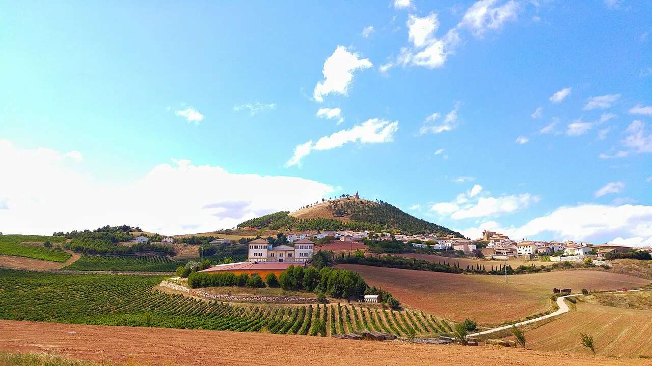 Landscape of fields and hills in Añorbe with blue sky and clouds.