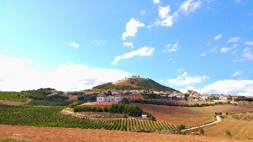 Paisaje de campos y colinas en Añorbe con cielo azul y nubes.