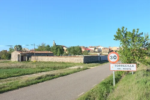 Access road to Torrecilla del Monte with speed limit sign and village view.