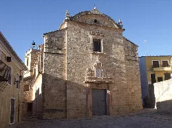 Stone church facade with balcony and large door in Montesa.
