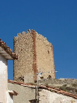 Steinerner Burgturm in La Hoz de la Vieja mit blauem Himmel.
