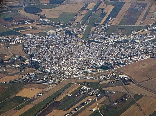 Luftaufnahme eines Ortes umgeben von Feldern und landwirtschaftlichen Flächen in Sevilla.