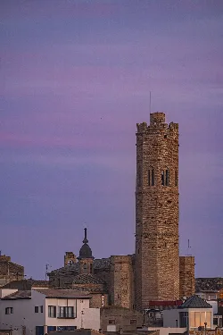 Torre de ladrillo con almenas en Tauste, Zaragoza, bajo un cielo morado y rosa.