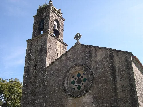 Fachada de una iglesia con torre y rosetón en la pared