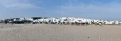Vista panorámica de la playa con arena y casas blancas en Conil de la Frontera.