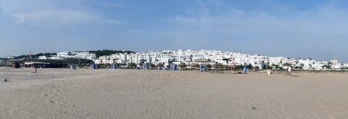 Panoramischer Blick auf den Sandstrand mit weißen Häusern in Conil de la Frontera.