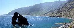 Roque de Bonanza en la costa de Valverde, con montañas y mar.