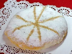 Round cake with powdered sugar and cinnamon decorations on top.