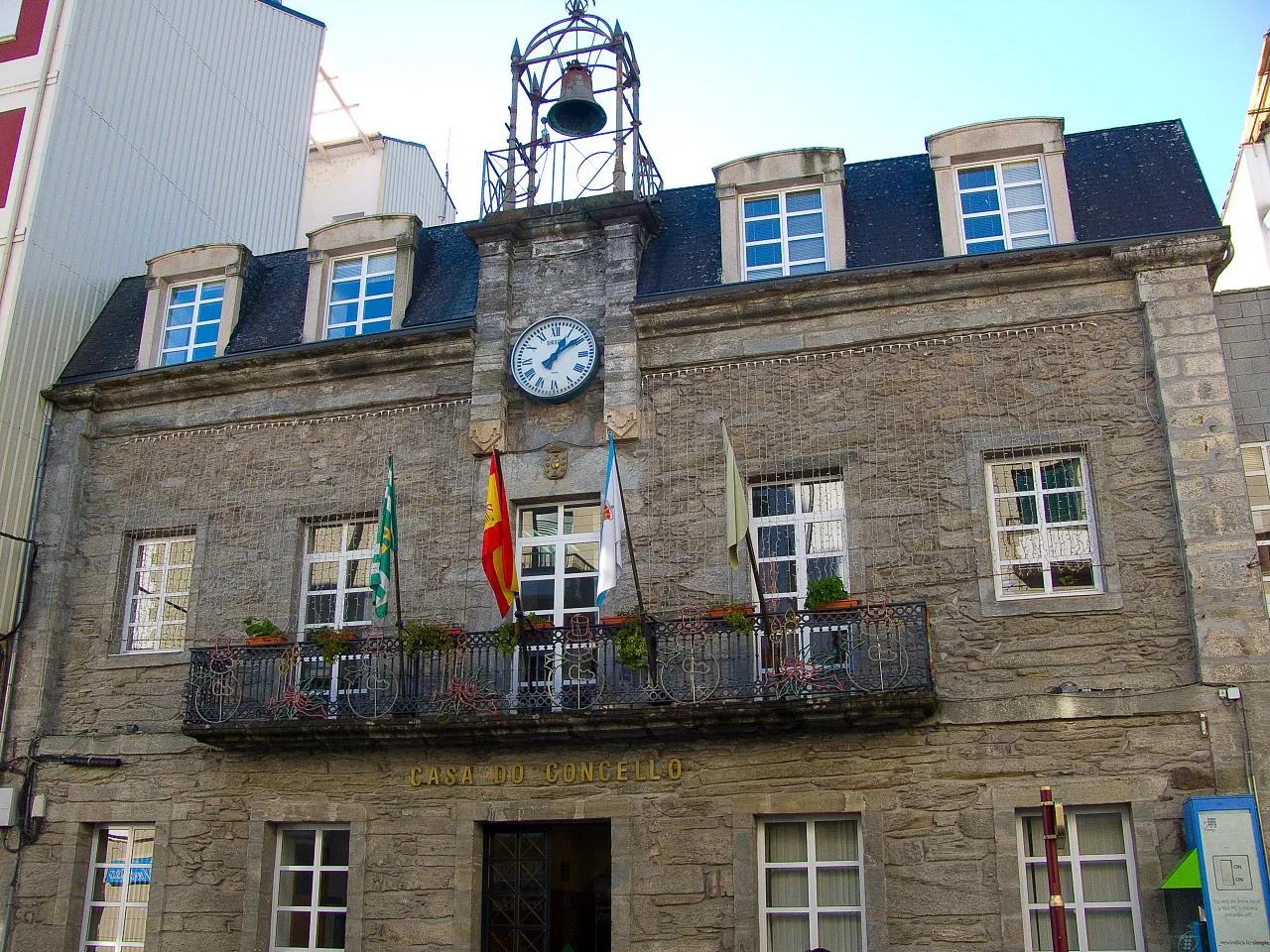 Steinernes Gebäude mit Uhr und Flaggen in Lugo.