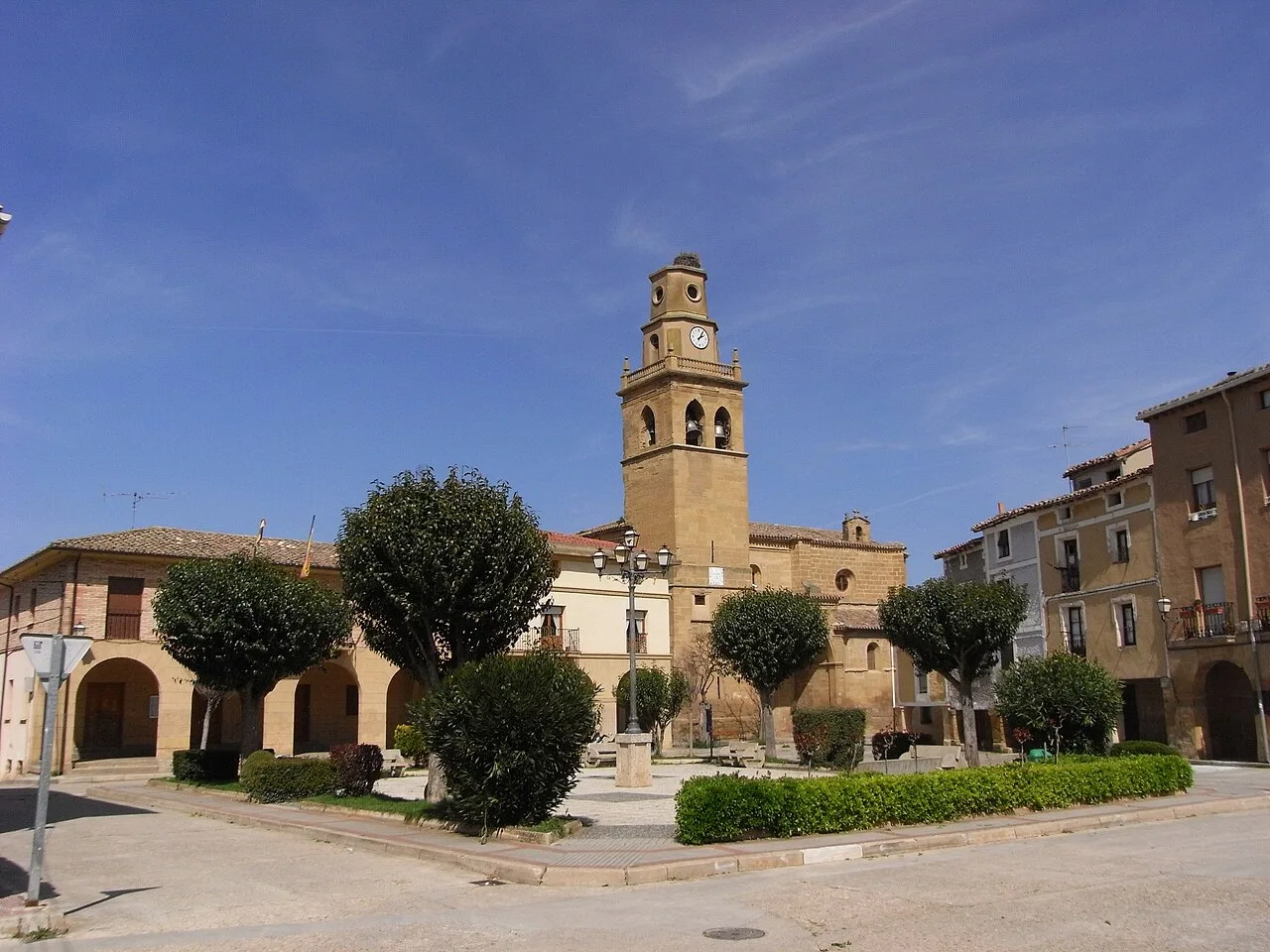 Iglesia de San Martín y plaza con árboles y edificios en Anguciana.