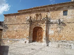 Stone church facade with wooden door and plaque.