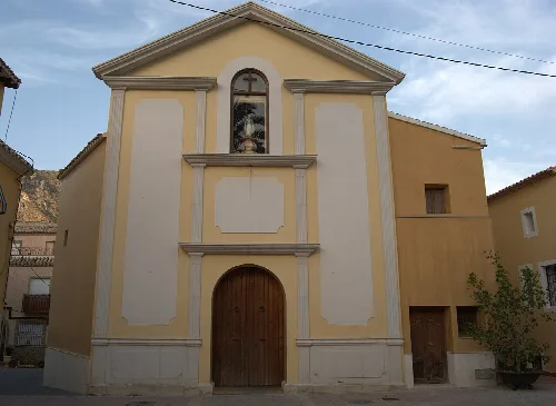Fassade einer Kirche mit Holztür und kleinen Fenstern in Ojós.