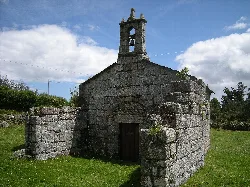 Small stone church with bell tower and old walls in Valle de Oro, Lugo.