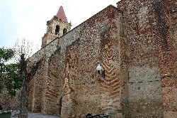 South facade of the parish church in Arroyo de San Serván, with brick walls and bell tower.