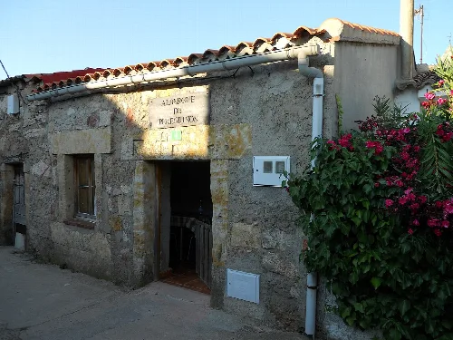 Kleine Steinhütte mit rosa Blumen an der Seite.