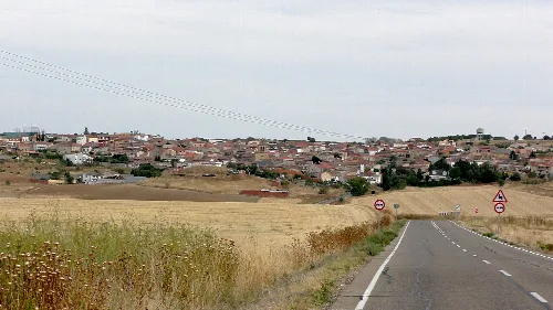 Straße mit Feldern und Dorf in der Ferne.