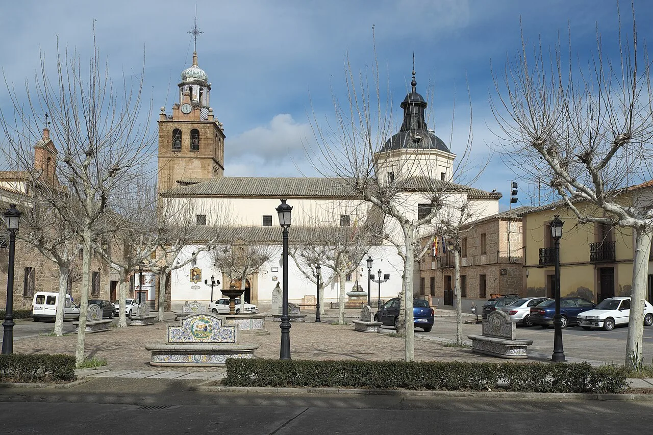 Katholische Pfarrkirche Santa Catalina mit Turm und Kuppel in einem Platz mit Bäumen und Bänken.