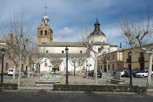 Santa Catalina Church with tower and dome in a square with trees and benches.