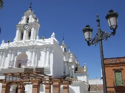 White church with tower and clock in Azuaga.