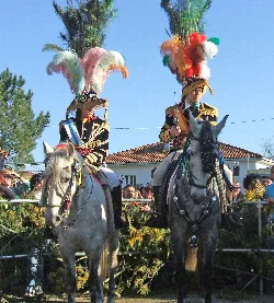 Dos personas en caballos con trajes y plumas en la cabeza en Vedra