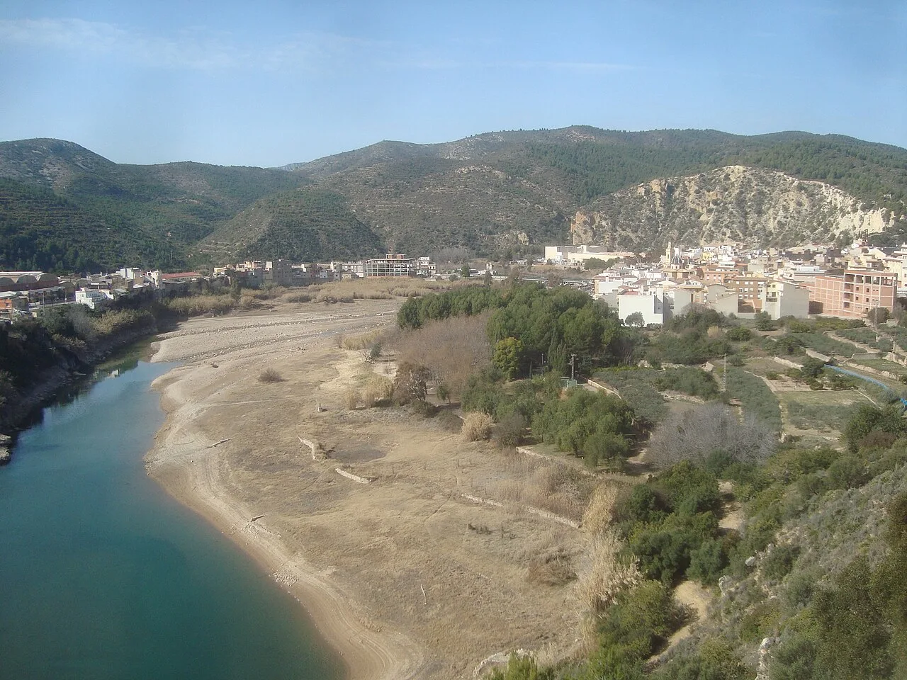 Paisaje con río, colinas y edificios en Ribesalbes.