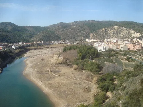Paisaje con río, colinas y edificios en Ribesalbes.