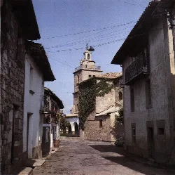 Calles estrechas con edificios antiguos y una iglesia en el fondo en Navascués.