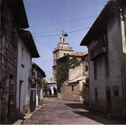 Narrow streets with old buildings and a church in the background in Navascués.