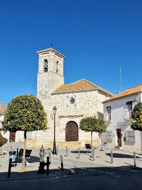 Kirche mit Turm und Bäumen auf dem Platz von Churriana de la Vega.