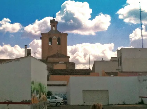 Blick auf eine Kirche in Castuera vom Parkplatz mit Wolken am Himmel.