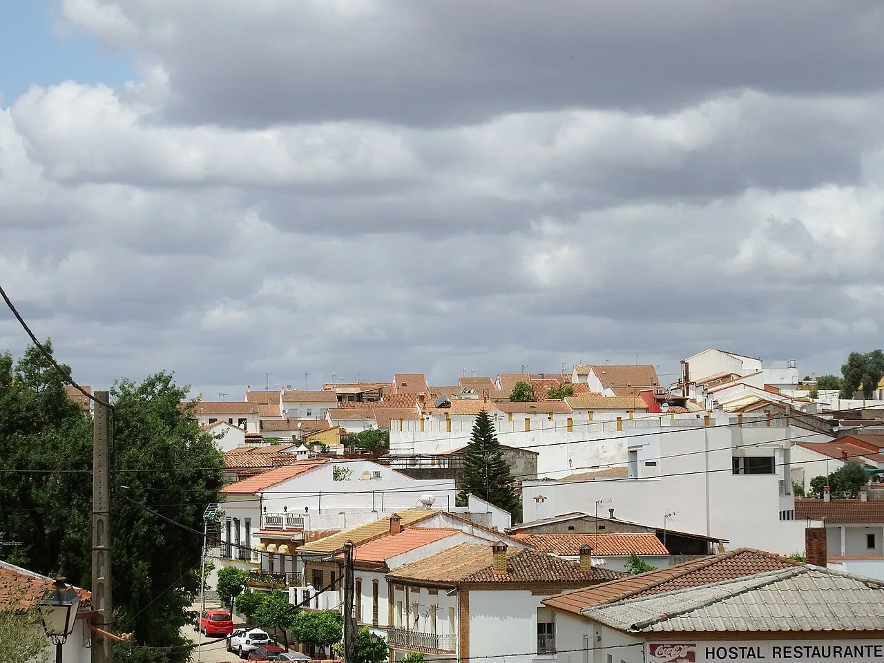 Vista de casas blancas y tejados rojos en Zalamea la Real bajo un cielo nublado.