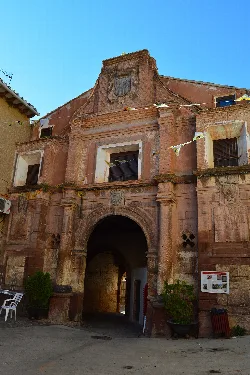 Fachada de un monasterio con arco de entrada y escudo en la parte superior.
