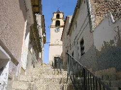 Clock tower of Monóvar on a steep street with stairs.