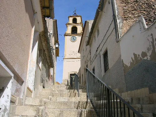Clock tower of Monóvar on a steep street with stairs.