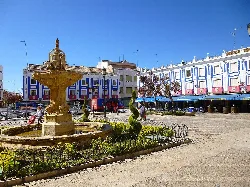 Fuente en la Plaza de España con edificios azules y blancos.
