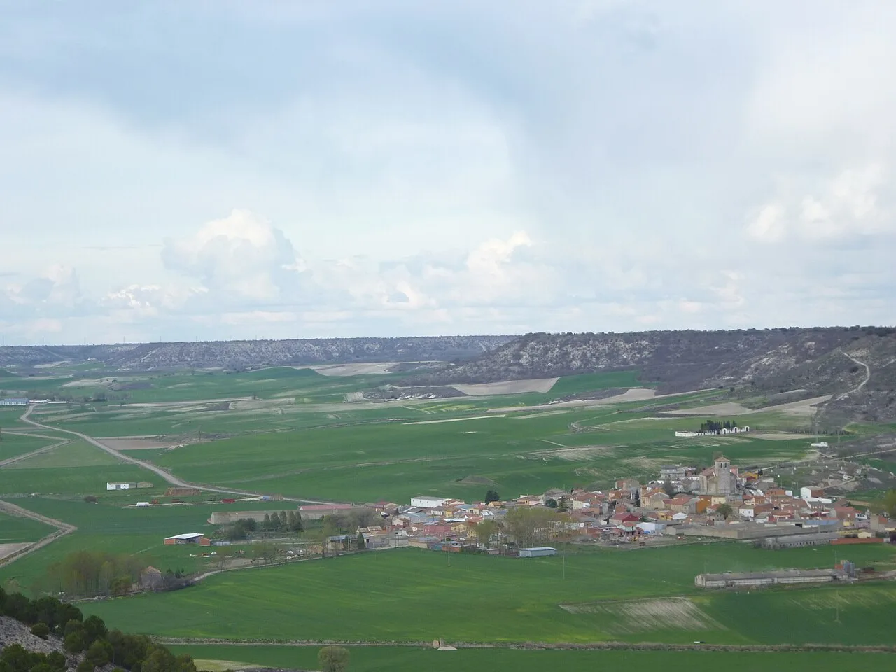 Panoramic view of Villavaquerín with green fields and village in the valley.