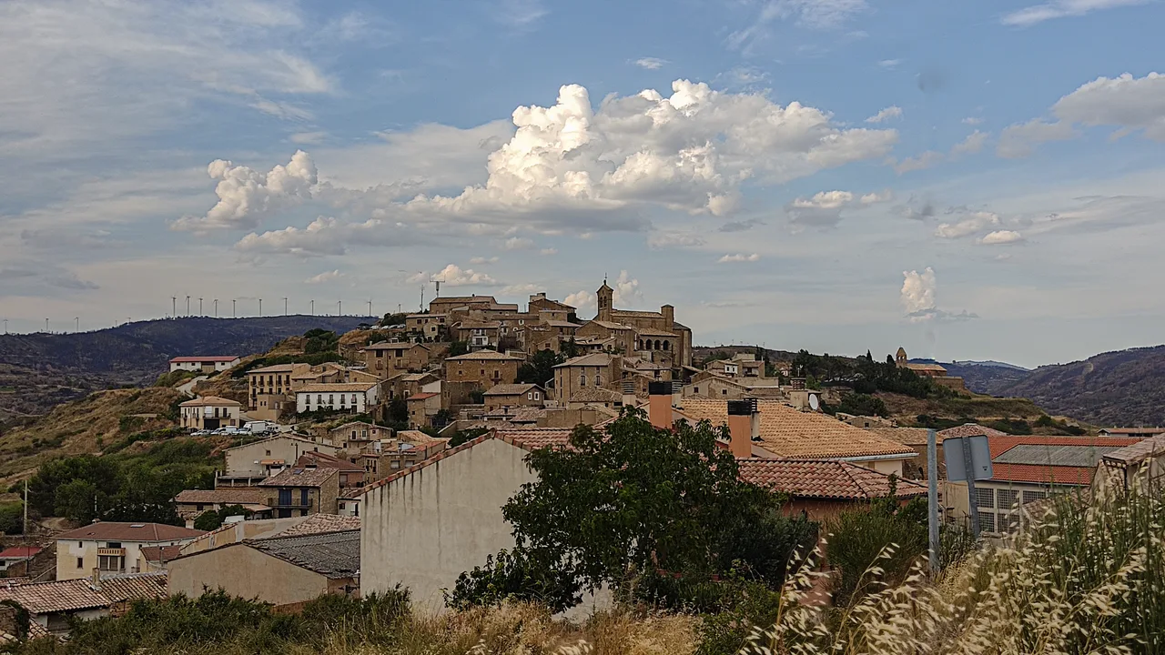 Panoramablick auf eine Stadt auf einem Hügel mit alten Gebäuden und bewölktem Himmel.