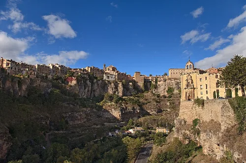 Häuser auf den Klippen von Cuenca unter einem blauen Himmel mit einigen Wolken.