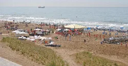 Playa con muchas personas, sombrillas y actividades en Castelldefels, Barcelona.