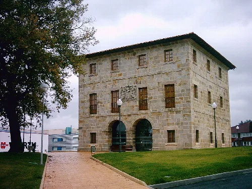Edificio de piedra con ventanas de madera y entrada con arcos en Zamudio.