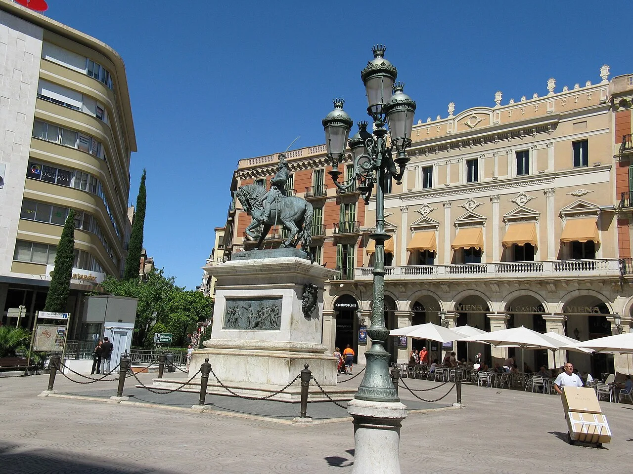 Joan Prim Statue in einem Platz mit Laternen und Cafés in Reus.