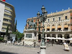 Joan Prim Statue in einem Platz mit Laternen und Cafés in Reus.