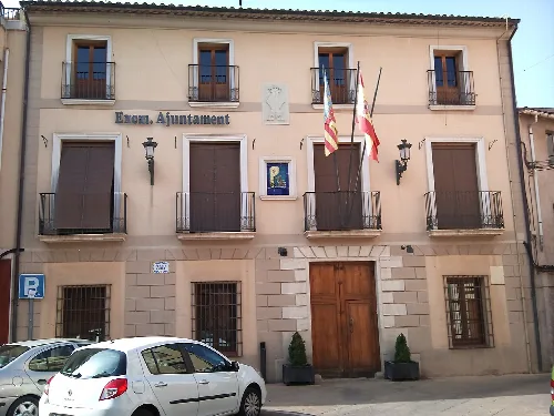 Building with stone facade and two flags on the town hall front.