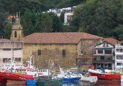 Iglesia de San Pedro con barcos en el puerto y casas en las colinas.