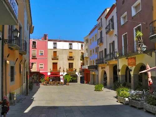 Platz mit bunten Gebäuden und Terrassen in Castelló d'Empúries.
